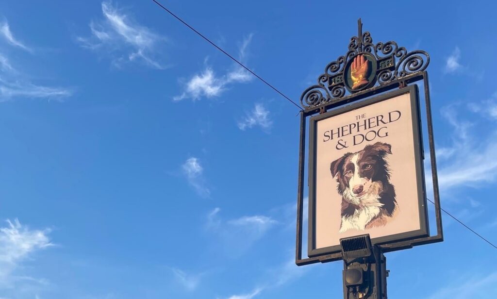 The Shepherd & Dog pub sign against a blue sky
